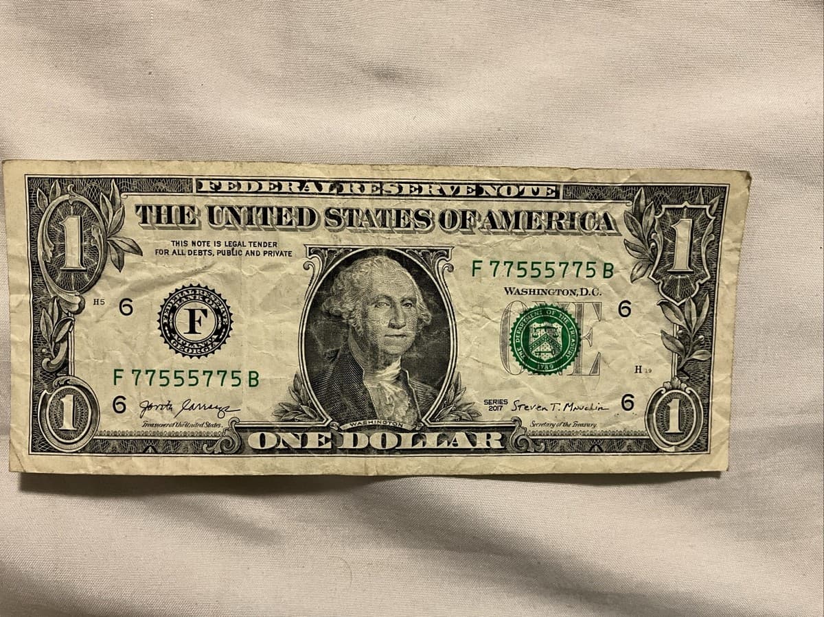 Real one-dollar bill with binary serial number 77555775, made from only 5s and 7s